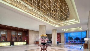 Eine großzügige Lobby mit einer Rezeption, hohen Säulen und einer dekorativen Decke.