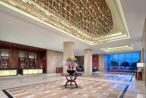 A spacious lobby with a reception desk, large columns, and a decorative ceiling.
