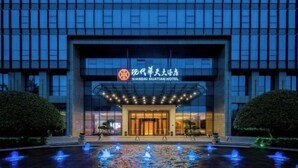 Das Xiandai Huatian Hotel mit moderner Fassade, großem Eingangsbereich und einem Wasserspiel im Vordergrund.