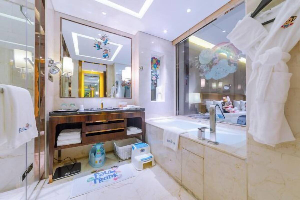 A modern bathroom with a large mirror, a bathtub, and a vanity with a sink.