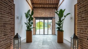 A hallway with brick walls, potted plants, and lanterns.