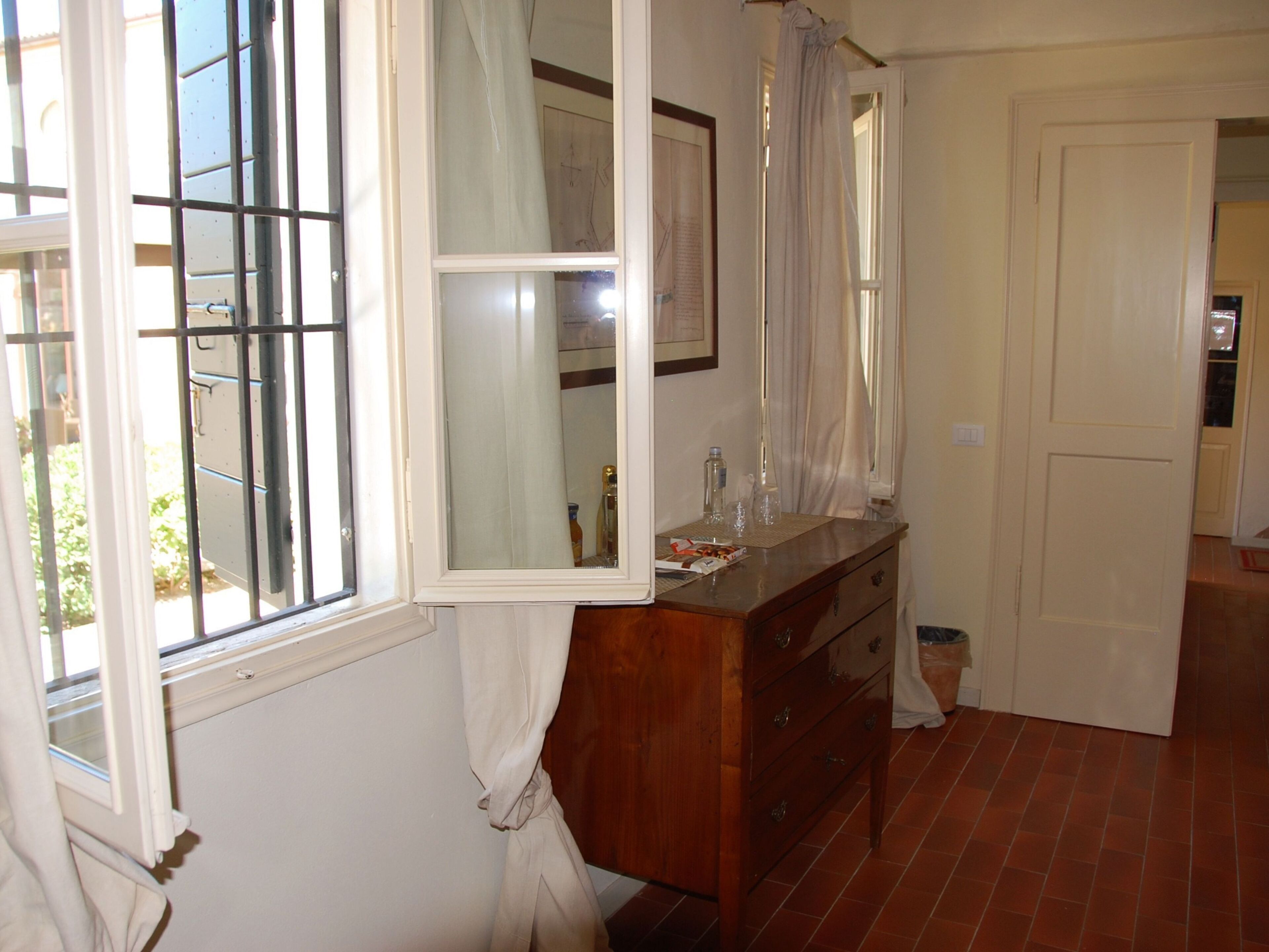 Una habitación con un aparador de madera, un espejo y una ventana con cortinas.