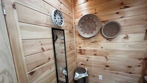 Ein Zimmer mit Holzwandverkleidung, einem Spiegel, zwei gewebten Körben und einem Mülleimer.