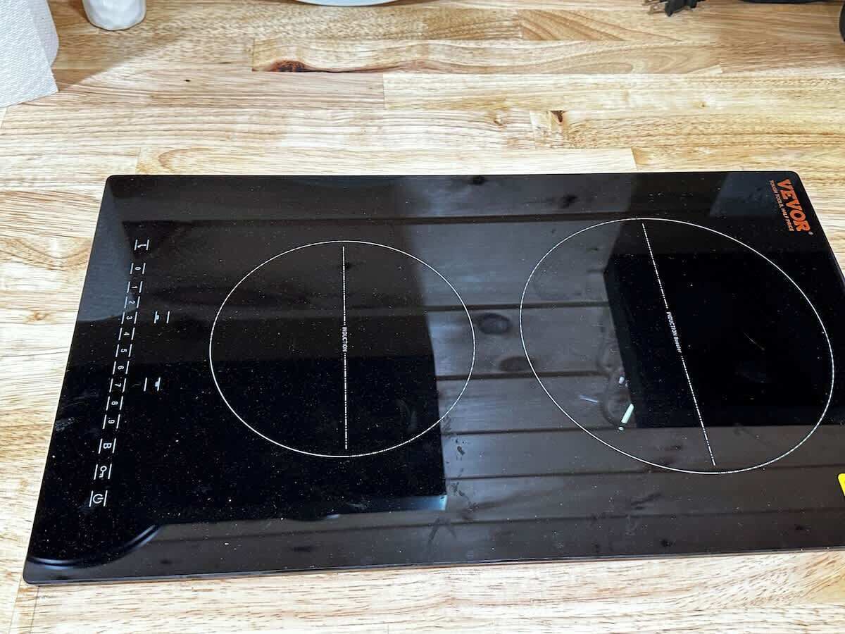 Una cuina d'inducció negra amb dues zones de cocció i un panell de control amb ajustos de temperatura.