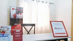 A hotel room with a bed, a table, and a chair. There are posters on the wall advertising RedDoorz. - RedDoorz Hostel @ Tita Aidz Inn Baguio (Baguio)