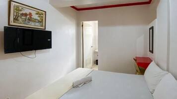 A hotel room with a bed, a TV mounted on the wall, and a door leading to another room.