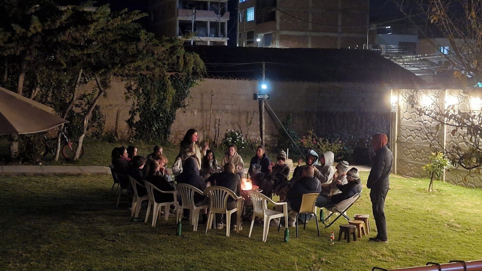 A group of people gathered around a fire in an outdoor setting at night.