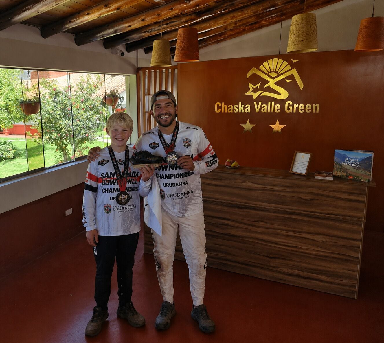 Two people standing in a room with a wooden reception desk and a sign that reads 'Chaska Valle Green.'