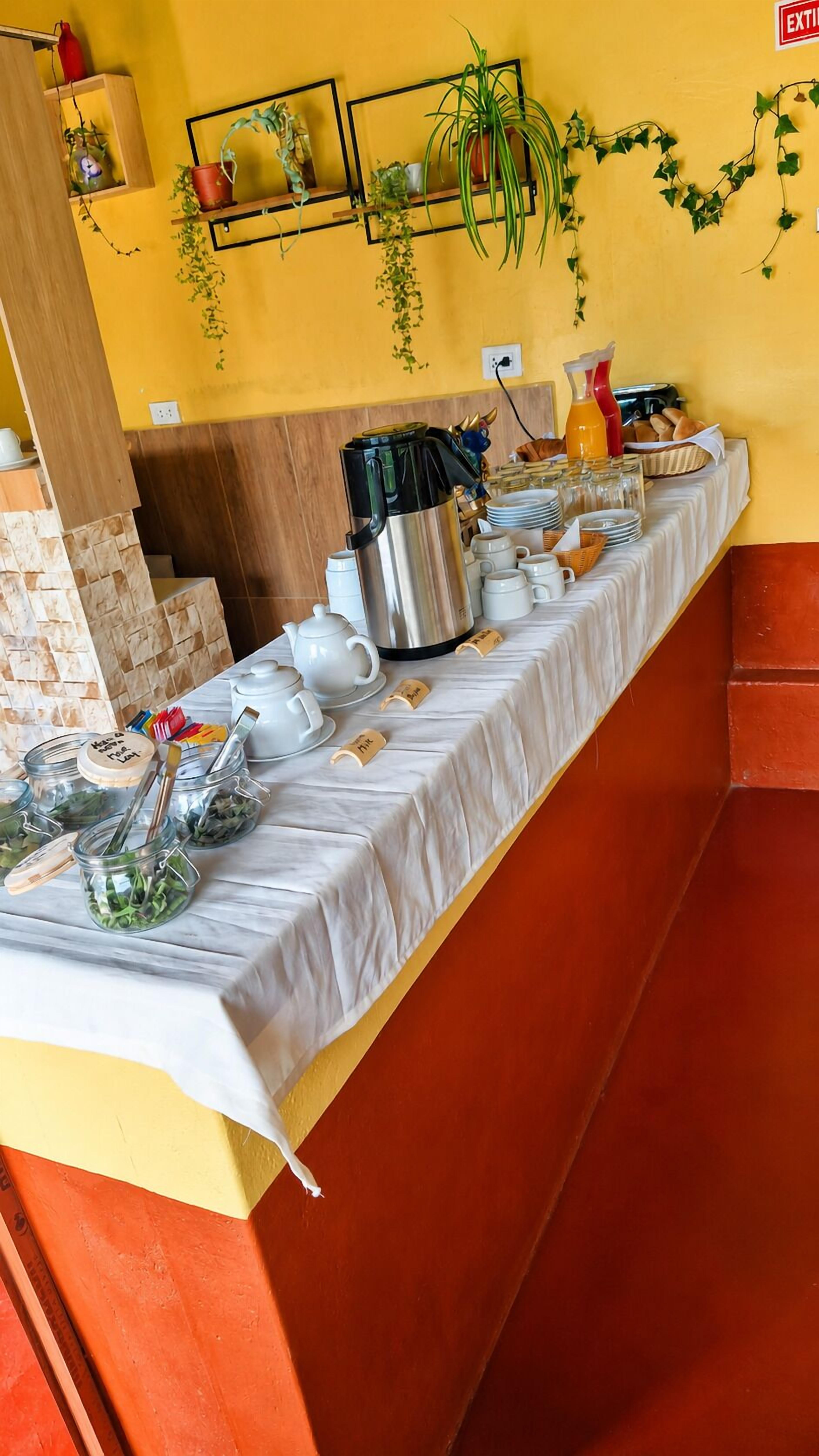 A buffet setup with a variety of food items, a coffee station, and a wall decorated with plants and a sign.
