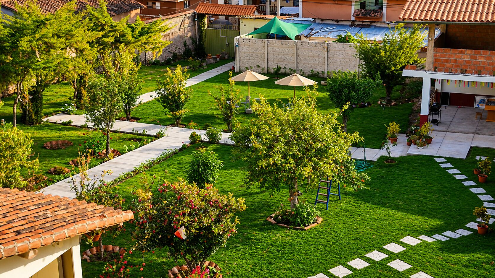 Un patio con un sendero pavimentado, un árbol pequeño y una sombrilla verde.