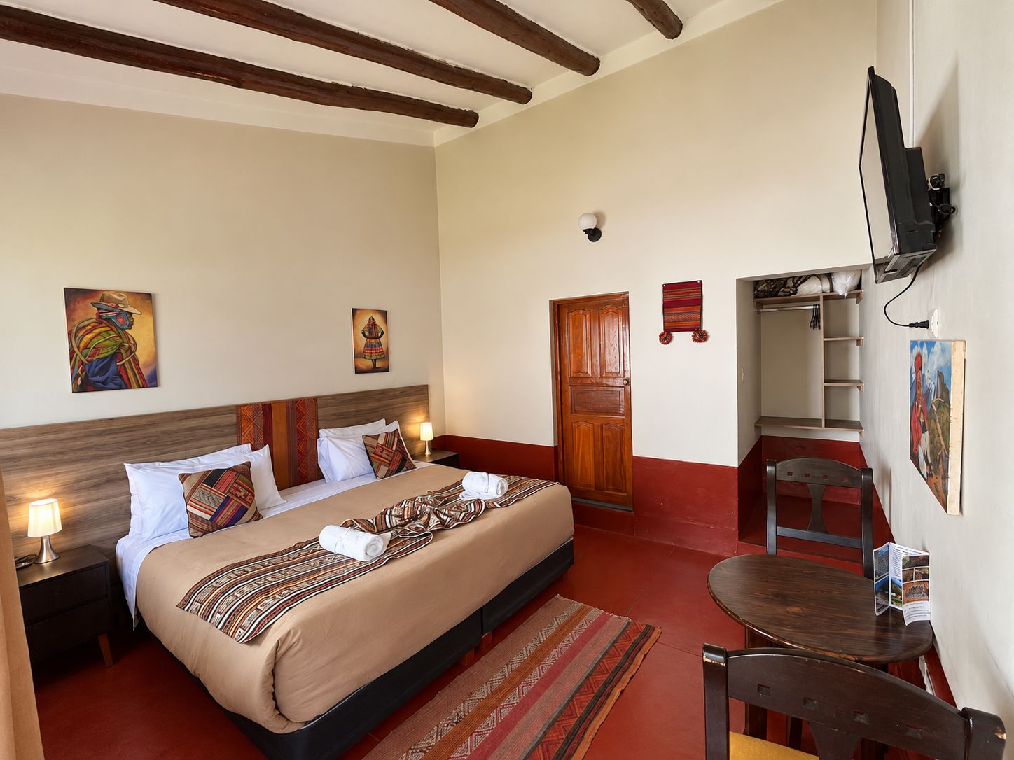 Una habitación de hotel con cama, mesita de noche, lámpara, obra de arte y televisor.