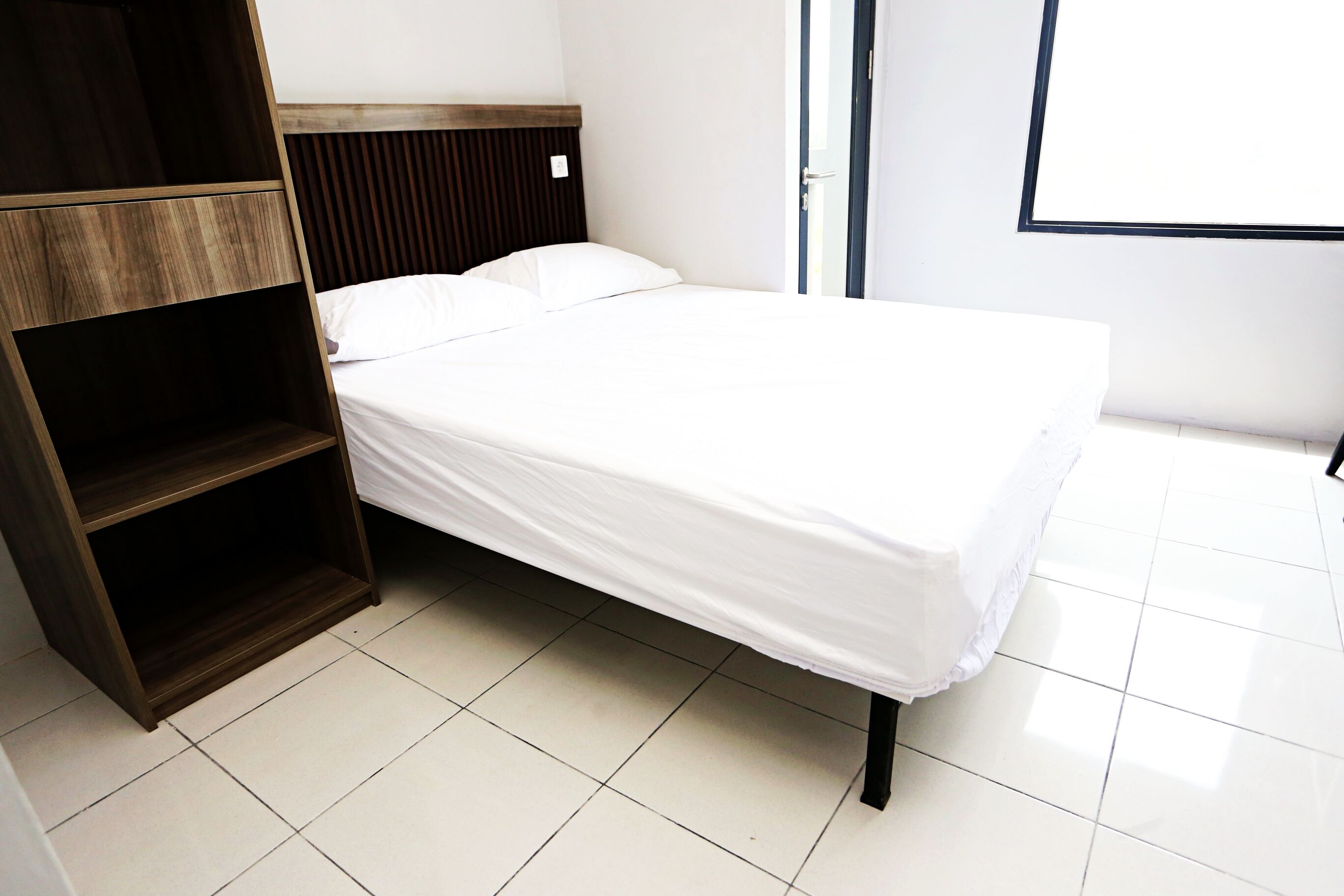 A neatly made bed with a wooden headboard and a built-in shelf unit.