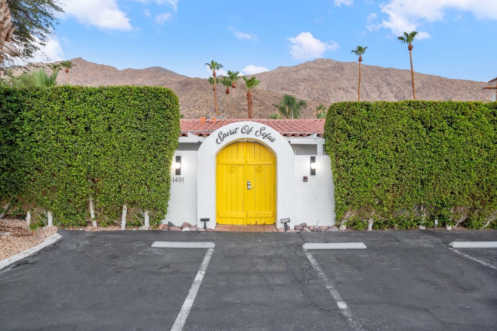 Un edificio con puerta amarilla, rodeado de follaje y un paisaje montañoso.