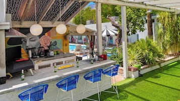 An outdoor bar area with a pool, bar stools, and a mural.