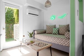 A modern living room with a sofa, a coffee table, and a wall-mounted air conditioner.