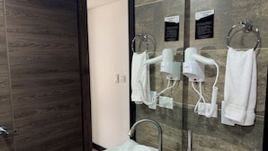Une salle de bain moderne avec deux lavabos, un grand miroir, un sèche-cheveux et un porte-serviettes.