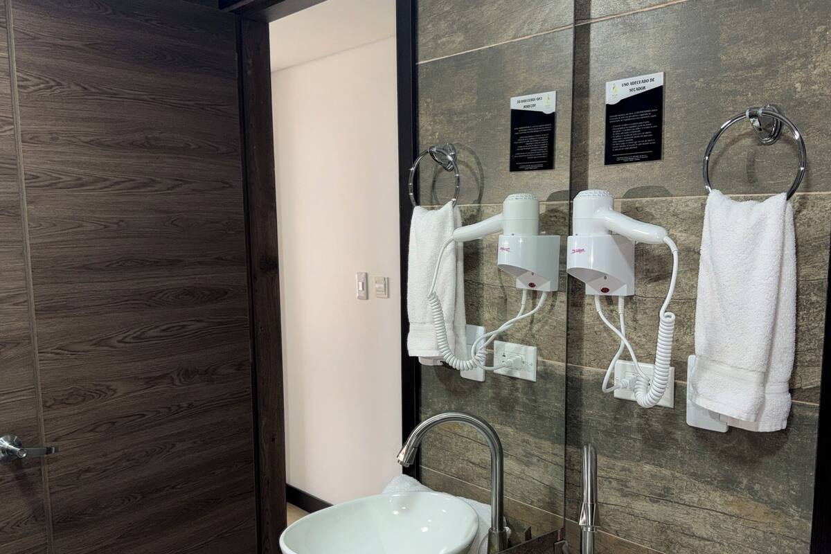 Ein modernes Badezimmer mit zwei Waschbecken, einem großen Spiegel, einem Fön und einem Handtuchhalter.