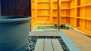 A wooden fence with a large planter and a stone pathway. - Cocon Setouchi (Suooshima)