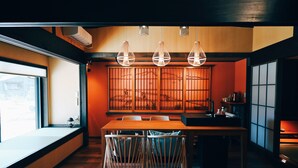 A modern kitchen with a wooden table and chairs, a built-in stove, and a large window. - Cocon Setouchi (Suooshima)