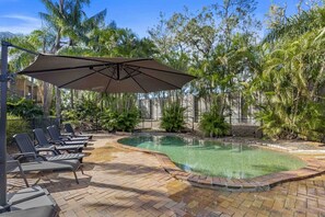 A swimming pool with lounge chairs and an umbrella, surrounded by lush greenery. - Spacious Room with Kitchen,WiFi, Easy Access 2 CBD (Mount Ommaney)