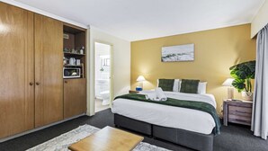 A hotel room with a bed, bedside table, lamp, and a large wardrobe. - Spacious Room Ideal for Biz District & Access CBD (Mount Ommaney)