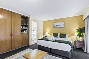 A hotel room with a bed, bedside table, lamp, and a large wardrobe. - Spacious Room Ideal for Biz District & Access CBD (Mount Ommaney)