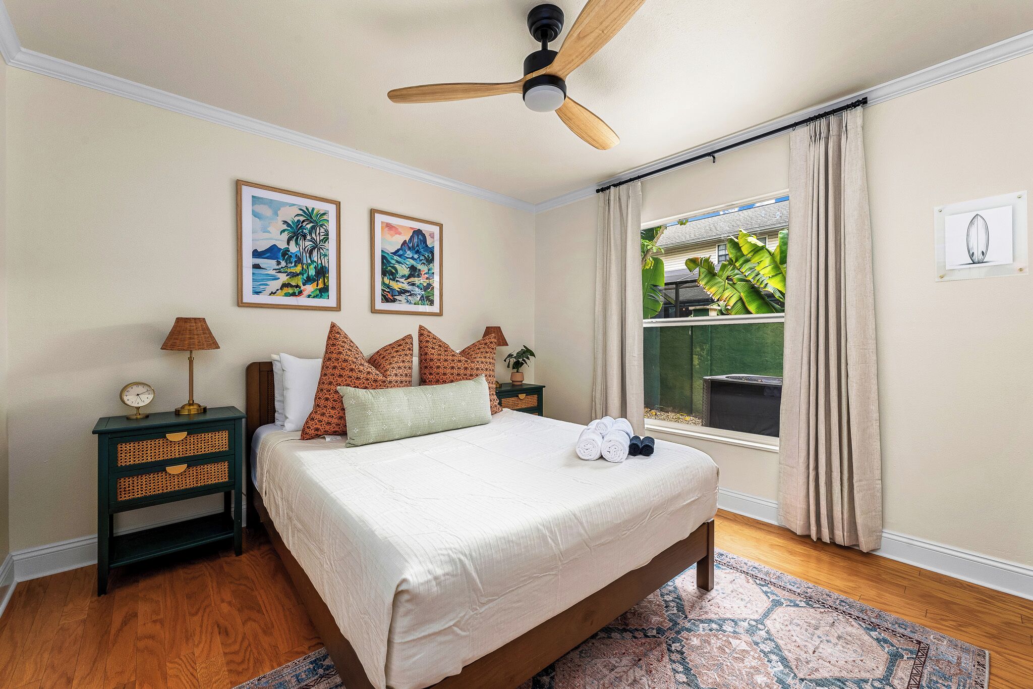 A bedroom with a bed, a nightstand, a ceiling fan, and a window with curtains.