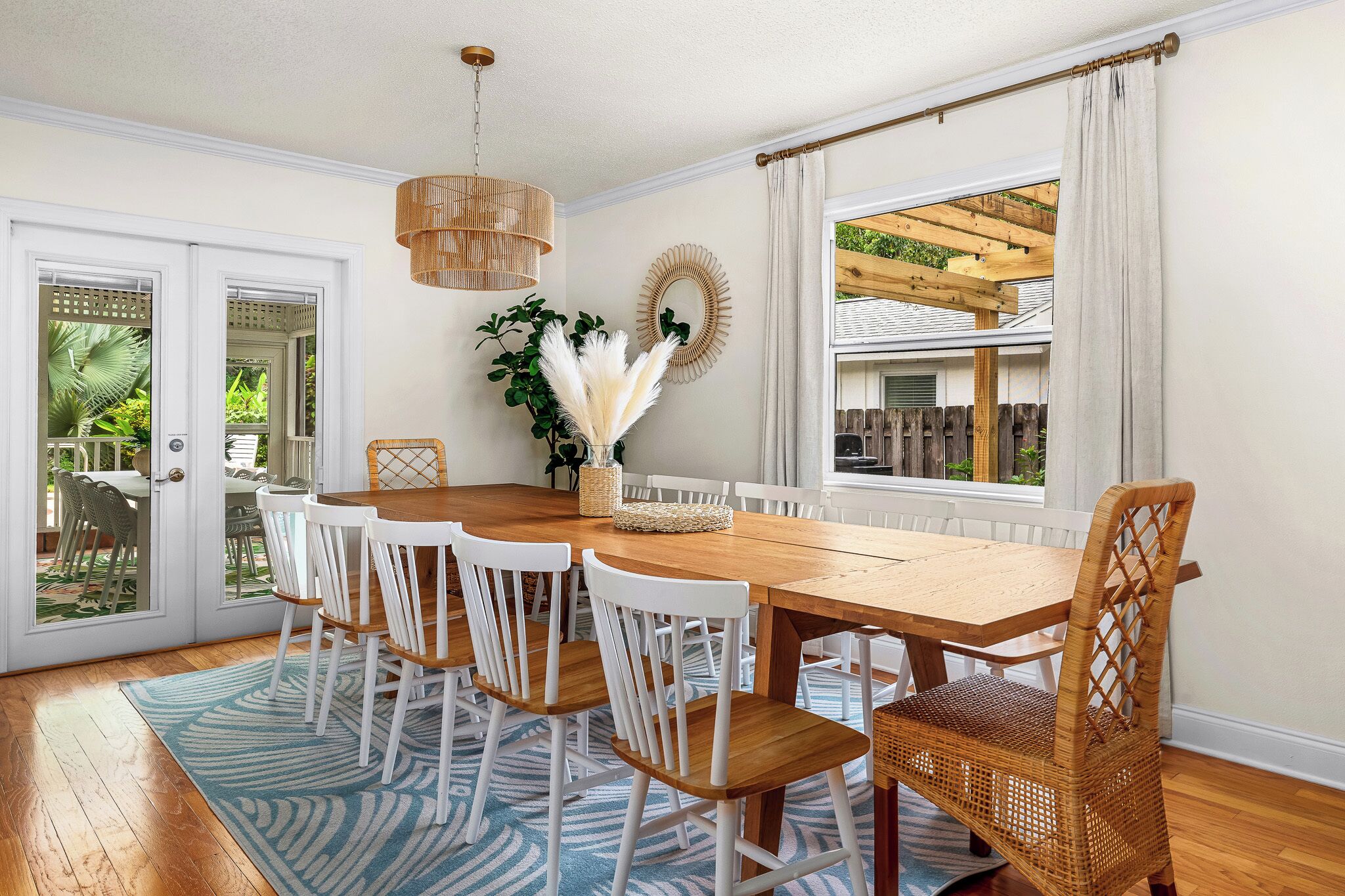 Een eetruimte met een houten tafel, witte stoelen, een rieten mand en een hanglamp.
