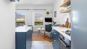 Una cocina moderna con comedor, televisor y vistas a montañas.