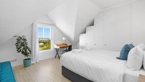 Un dormitorio moderno con una cama grande, un escritorio y una planta en maceta.