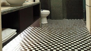 Un bagno con pavimento a scacchi, un lavandino con specchio, un WC e una doccia.