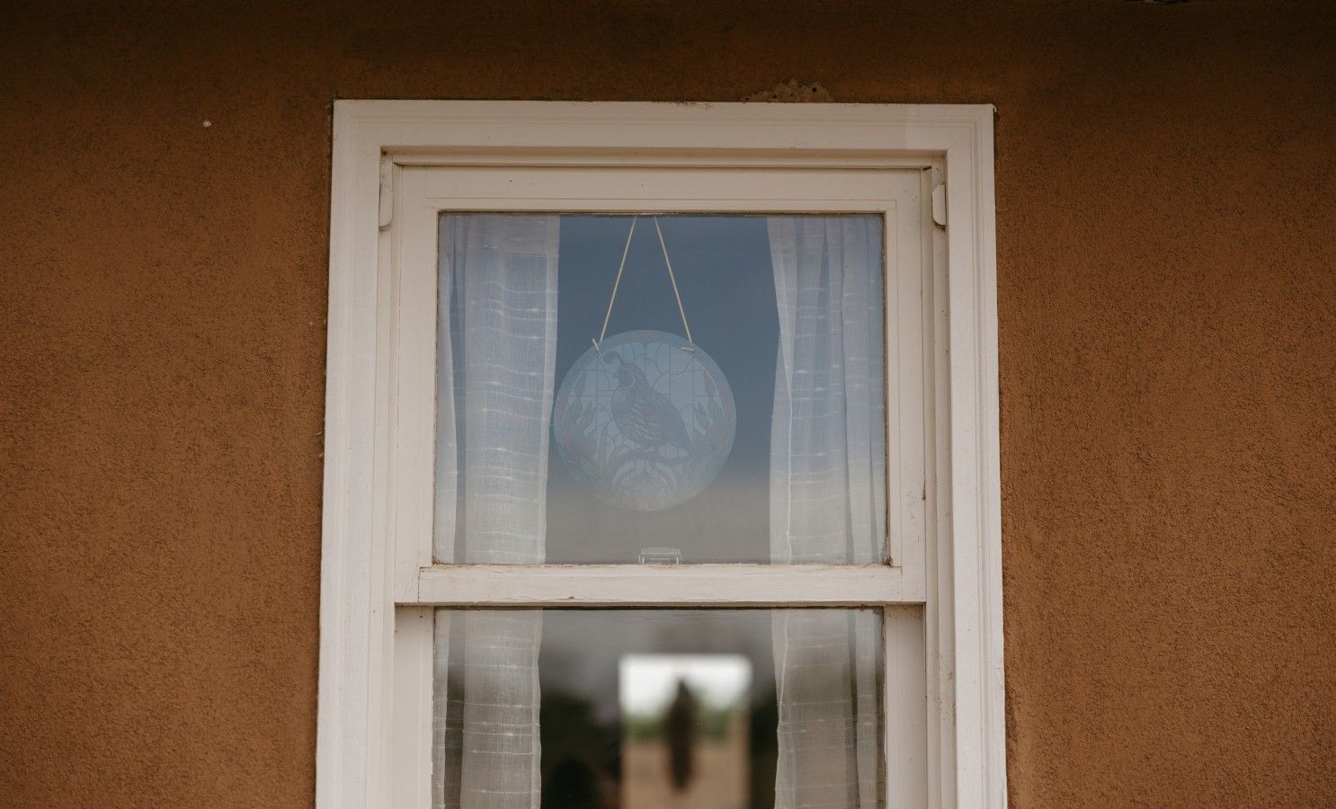 A window with a globe ornament hanging from the top.