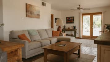 A living room with a sofa, coffee table, and a ceiling fan.