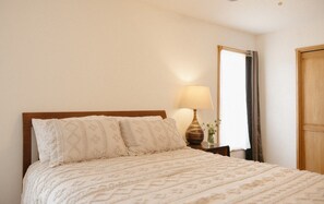 Un lit avec une tête de lit en bois, une lampe de chevet et un miroir au mur.
