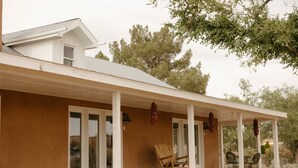 Een huis met een overdekte veranda, een schommelstoel en een eettafel met stoelen.