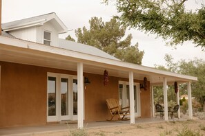 Une maison avec un porche abrité, une chaise berçante et une table à manger avec des chaises.