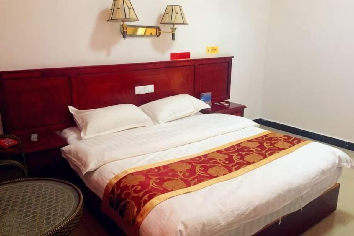 Une chambre d’hôtel avec un grand lit, une table de chevet, une lampe et un luminaire fixé au mur.