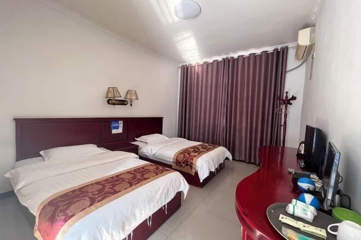 Une chambre d’hôtel avec deux lits, un bureau, une télévision et un rideau.