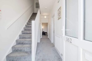 A staircase leading to a landing with a door marked '162' and a hallway with a carpeted floor. - Large 3 Bed Home With 2 Living Areas & Sofa Bed (Northampton)