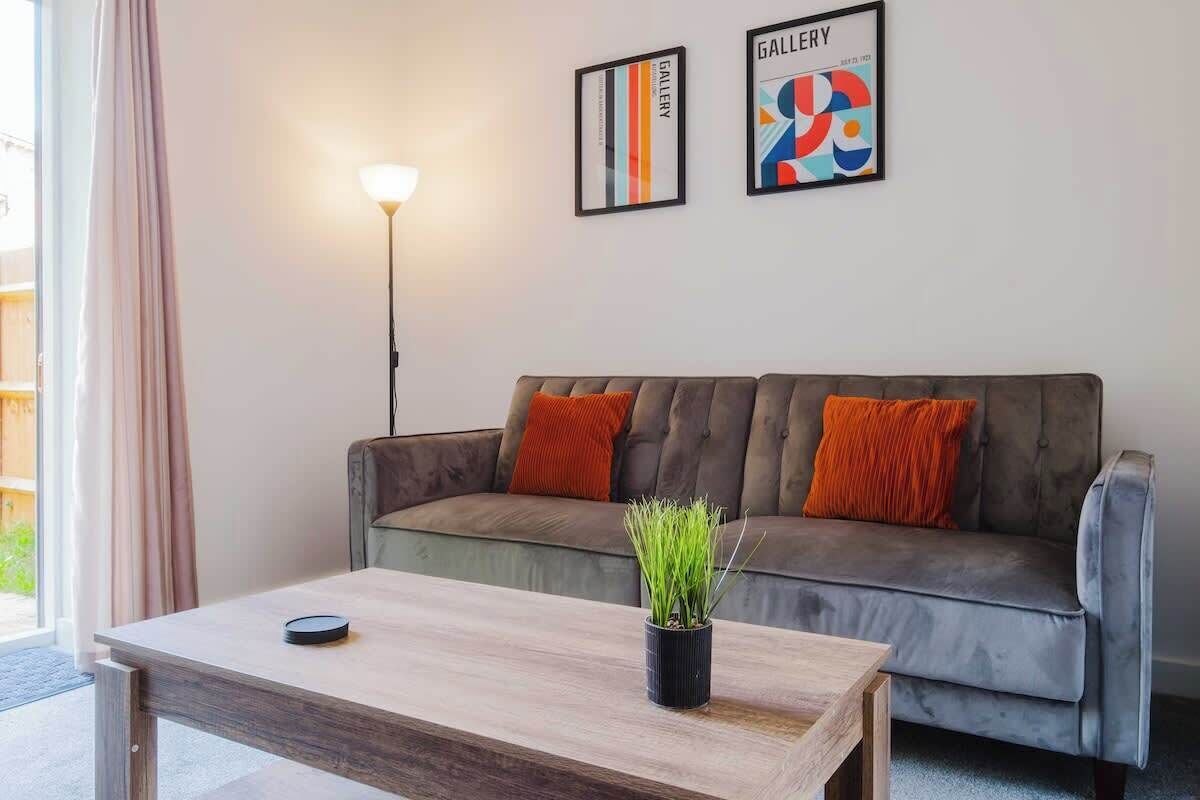 A modern living room with a grey sofa, a wooden coffee table, and a potted plant.
