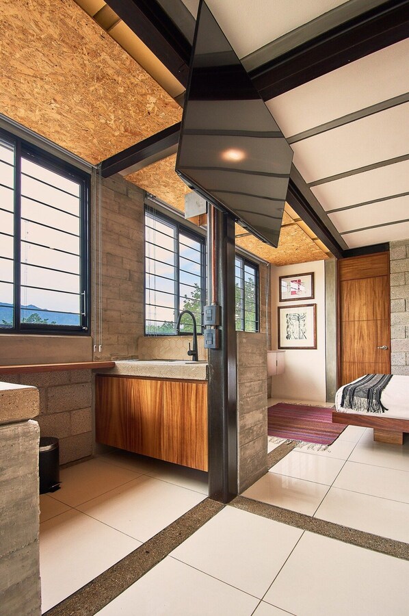 A modern interior with a kitchen area, large windows, and a bed.