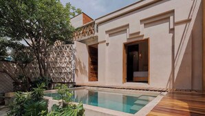 Un espace piscine moderne avec une terrasse en bois, une clôture aux lignes géométriques et une végétation luxuriante.