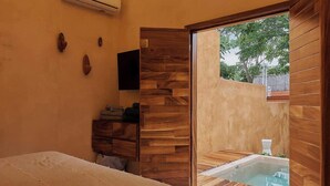 Une chambre avec un lit, une armoire en bois, un appareil de climatisation et une vue sur un jacuzzi situé à l’extérieur.