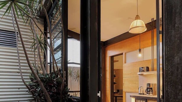 A modern interior with a staircase leading to a kitchen area, featuring a dining table and bar setup.
