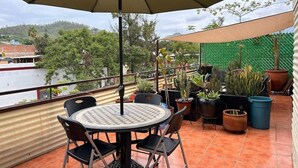 A patio with a round table and chairs, an umbrella, and potted plants.