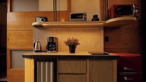 A compact kitchen with a built-in microwave, a coffee maker, and a small potted plant on the countertop.