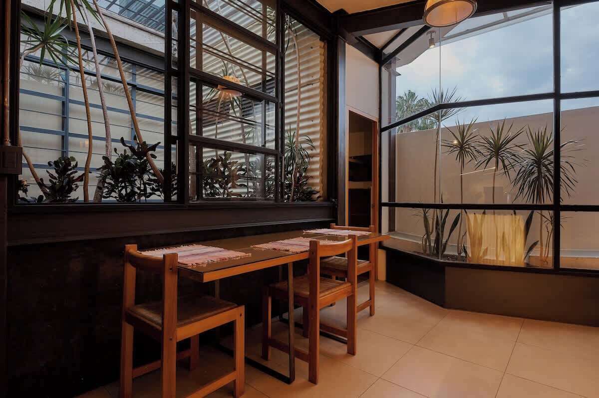 A corner room with a large window, wooden table, and chairs.