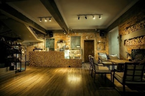 A cozy interior with a wooden bar counter, seating area, and exposed brick walls. - Olive Tree Coffee Inn (Haikou)