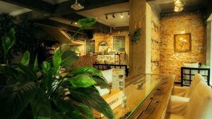Un restaurant avec un mur en briques, des luminaires suspendus et une table en bois.