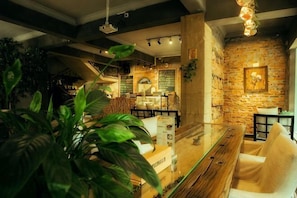 A restaurant with a brick wall, hanging lights, and a wooden table. - Olive Tree Coffee Inn (Haikou)